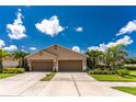 Two-car garage twin villa with a well-maintained lawn and tropical plants at 8883 Tuscany Isles Dr, Punta Gorda, FL 33950