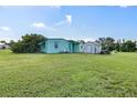 Exterior view of property with green grass, storage shed, propane tank, and lush vegetation at 3107 Easy St, Port Charlotte, FL 33952