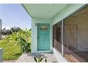 Charming home featuring a turquoise front door and a spacious, sunlit porch with tropical landscaping at 3107 Easy St, Port Charlotte, FL 33952