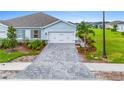 Light blue home with a paved driveway, green grass, well-maintained landscaping, and a two-car garage at 1781 W Palms Dr, Port Charlotte, FL 33953