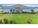 Single-story home boasting a green lawn and colorful landscaping complemented by a stone accent wall and light blue paint at 1781 W Palms Dr, Port Charlotte, FL 33953