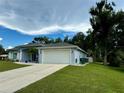 One-story light blue house with white garage and landscaping at 18265 Koala Ave, Port Charlotte, FL 33948