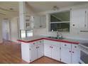 Kitchen with white cabinets, double sink, and wood-look flooring at 5787 Holiday Park Blvd, North Port, FL 34287
