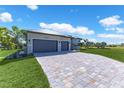 Modern home features an expansive driveway and a lush lawn, enhanced by tropical landscaping at 24051 Pyramid Way, Punta Gorda, FL 33955