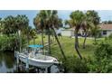 Private backyard with lush greenery, tall palm trees, a private boat dock and home access at 2256 Auburn Blvd, Port Charlotte, FL 33948