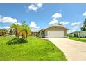 Tan house with a large grassy yard, palm tree, and a two-car garage at 20222 Banner Ave, Port Charlotte, FL 33952