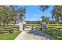 Long driveway with a wooden fence and black gate at 15300 Water Oak Ct, Punta Gorda, FL 33982