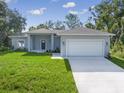 Newly constructed one-story home with gray exterior, two-car garage, and lush lawn at 1326 New London St, North Port, FL 34288