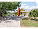 Bright yellow house with a large driveway, brick pavers, and a view of a canal at 24395 Suncoast Blvd, Punta Gorda, FL 33980