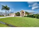 Tan house with metal roof, double door entry, and palm trees at 7369 Schefflera, Punta Gorda, FL 33955