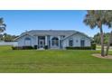 Single story home with light blue exterior, lush lawn at 18415 Alphonse Cir, Port Charlotte, FL 33948