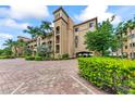 Three-story building with a Mediterranean design, lush landscaping, and parking area at 89 Vivante Blvd # 305, Punta Gorda, FL 33950
