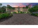 Evening view of a three-story building with Mediterranean styling, landscaping, and brick pavers at 89 Vivante Blvd # 305, Punta Gorda, FL 33950