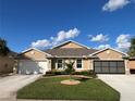 Two-car garage home with a tan exterior and landscaping at 25168 E Lenox Cir, Punta Gorda, FL 33950