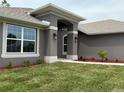 Home's entry with manicured landscaping, stucco columns, and wall-mounted lights at 49 Tee View Rd, Rotonda West, FL 33947