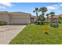 Charming one-story home with a two-car garage, tile roof, and beautifully landscaped yard with palm trees at 13064 Creekside Ln, Port Charlotte, FL 33953