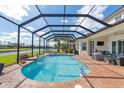 Covered pool and brick patio, with a serene view of the lake and lush greenery at 5241 Grand Palmetto Way, North Port, FL 34291