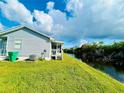 Backyard view of a home overlooking a canal, lush grass, and screened porch at 14300 Worthwhile Rd, Port Charlotte, FL 33953