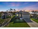 Twilight shot of single-story home with fresh landscaping and bright exterior lighting at 4255 Oak Terrace Cir, Port Charlotte, FL 33953
