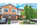 Two story townhome with orange exterior, two car garage, and landscaped front yard at 20149 Lagente Cir, Venice, FL 34293