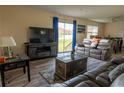 Spacious living room featuring a large TV, comfortable seating, and sliding glass doors leading to the backyard at 860 Columbia St, Port Charlotte, FL 33948