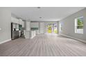 Bright living room with luxury vinyl plank floors, and a modern kitchen with stainless steel appliances at 2404 Hanford Ln, North Port, FL 34288