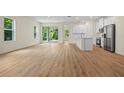 Bright open living room showcasing wood-look flooring and a seamless transition to the kitchen with natural light at 3390 Nadasky Ave, North Port, FL 34288