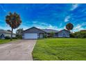 Gray house with white garage door and landscaping, long driveway at 1256 Alton Rd, Port Charlotte, FL 33952