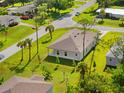 An aerial view of a single-Gathering home with a covered patio, green lawn, and mature palm trees at 1293 Preston St, Port Charlotte, FL 33952