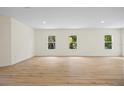 Bright living room featuring wood-look floors and three large windows at 1415 Nackman Rd, North Port, FL 34288