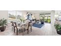 Bright dining room with a silver dining table, white chairs and decor plus a view into the living room at 16402 Bridle Ridge St, Port Charlotte, FL 33953