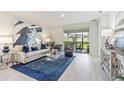 This bright living room features stylish decor, a blue accent rug, and sliding glass doors to the outside patio at 16402 Bridle Ridge St, Port Charlotte, FL 33953