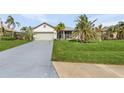Charming single-story home featuring a well-manicured lawn, mature palm trees, and an attached two-car garage at 24004 Vincent Ave, Punta Gorda, FL 33955