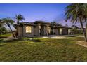 Single-story home with tile roof, palm trees, and a well-manicured lawn at dusk at 25373 Tether Ln, Punta Gorda, FL 33983