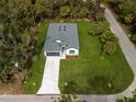 Aerial view of a well-maintained single-story home with a spacious lawn and driveway in a wooded area at 3705 Baynes Rd, North Port, FL 34288