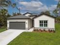 Charming single-story home with a well-manicured lawn, gray two-car garage, and tastefully landscaped front yard at 3705 Baynes Rd, North Port, FL 34288