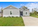 Gray house with white accents, landscaped lawn, and a paved driveway at 1497 Nordendale Blvd, North Port, FL 34288