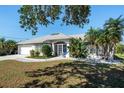 Single story home with a two-car garage, mature landscaping, and a light gray exterior at 650 Chamber Nw St, Port Charlotte, FL 33948