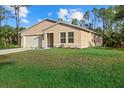 Tan house with white garage door and lush green lawn at 14220 Dunlap Ave, Port Charlotte, FL 33953