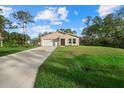 Tan house with a white garage door and a large green yard at 14220 Dunlap Ave, Port Charlotte, FL 33953
