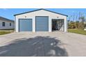 View of the exterior of the large garage with blue doors and ample parking space at 17152 Wintergarden Ave, Port Charlotte, FL 33948