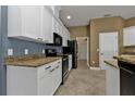 Modern kitchen features white cabinets, granite countertops, and black appliances at 17152 Wintergarden Ave, Port Charlotte, FL 33948