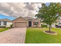 Tan house with red shutters, a two-car garage, and a manicured lawn at 28022 Arrowhead Cir, Punta Gorda, FL 33982