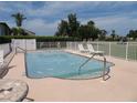 Community pool with lounge chairs and surrounding fence at 1360 Rio De Janeiro Ave # 117, Punta Gorda, FL 33983