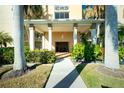 Inviting building entrance with lush landscaping, stately columns, and covered walkway leading to a seating area at 1650 W Marion Ave # 144, Punta Gorda, FL 33950
