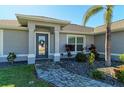 Front entrance with a walkway, landscaping, and a gray door at 21341 Edgewater Dr, Port Charlotte, FL 33952