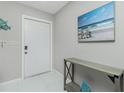 Bright and inviting entryway with a decorative table, beach-themed artwork, and clean, white tile flooring at 2190 Taunt St, Port Charlotte, FL 33948