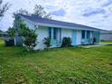 Front view of a single-story home with teal accents and a grassy yard at 683 W Tarpon Nw Blvd, Port Charlotte, FL 33952