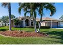 Single-story home with two-car garage, manicured lawn, and palm trees at 712 Boundary Blvd, Rotonda West, FL 33947