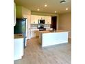 Bright kitchen featuring stainless steel appliances, white cabinetry, an island and wood-look flooring at 9531 Turtle Grass Cir, Punta Gorda, FL 33950